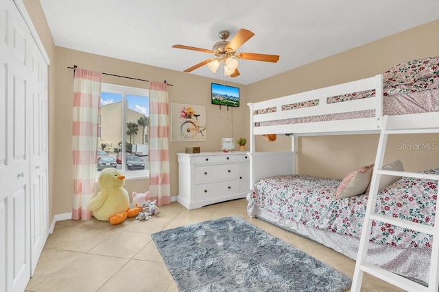 tiled bedroom with ceiling fan and a closet