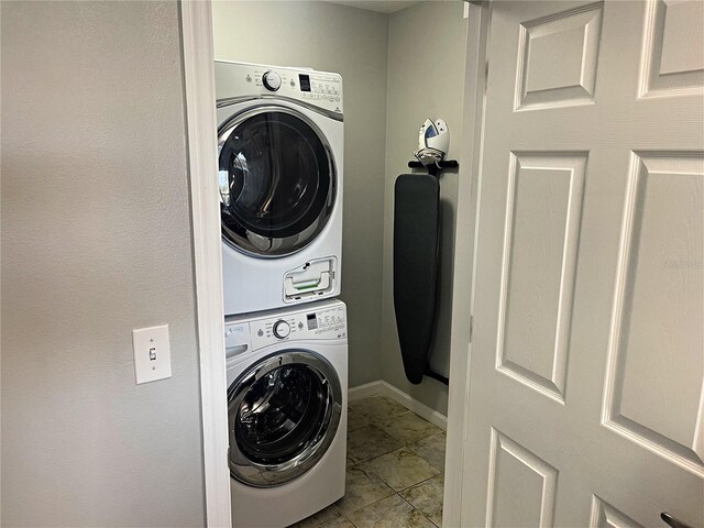 washroom featuring light tile patterned flooring and stacked washer and dryer