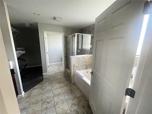 bathroom featuring a textured ceiling and separate shower and tub