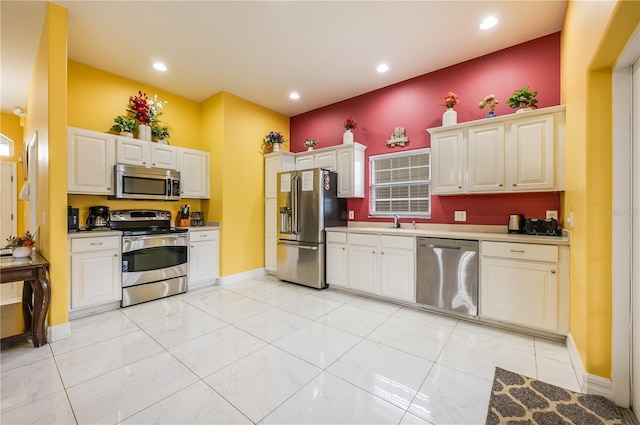 kitchen with light tile patterned flooring, sink, stainless steel appliances, and white cabinetry