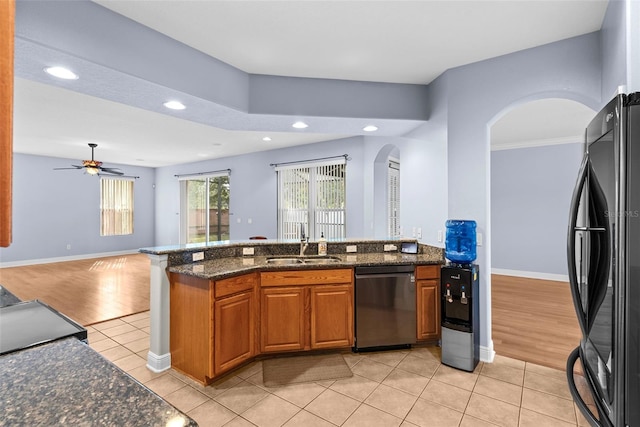 kitchen with dark stone countertops, light tile patterned floors, sink, and black appliances