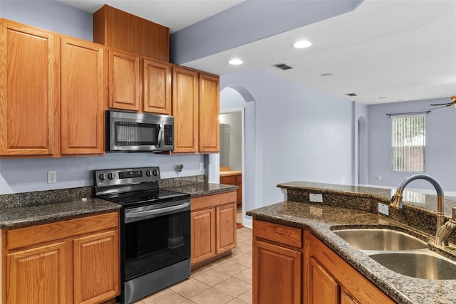 kitchen featuring sink, appliances with stainless steel finishes, dark stone counters, and light tile patterned floors