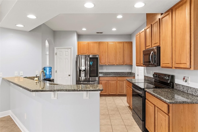 kitchen featuring appliances with stainless steel finishes, sink, dark stone counters, and a kitchen breakfast bar