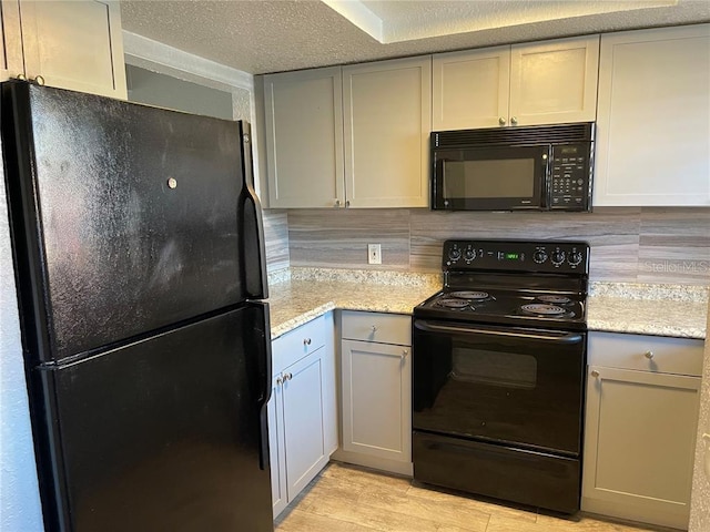 kitchen with light stone counters, a textured ceiling, decorative backsplash, and black appliances