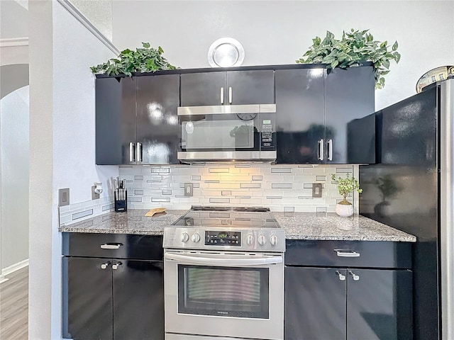 kitchen featuring decorative backsplash, light stone countertops, stainless steel appliances, and light wood-type flooring