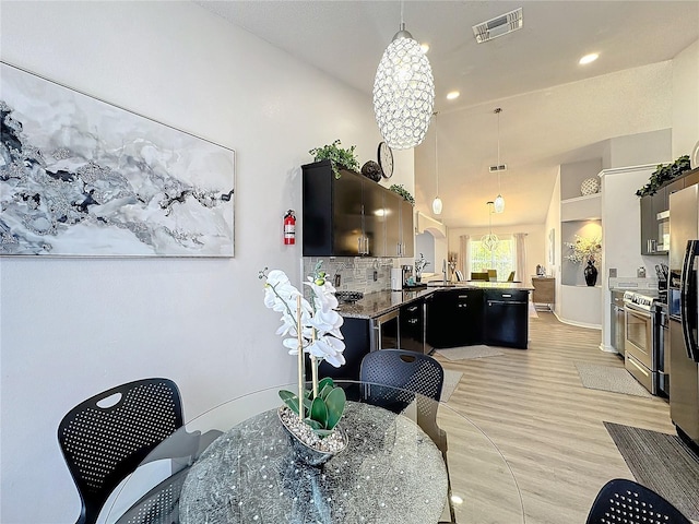 dining space with high vaulted ceiling, sink, an inviting chandelier, and light hardwood / wood-style flooring