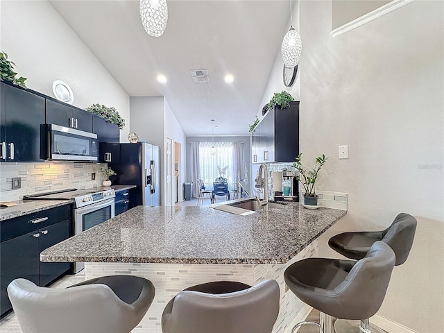 kitchen with tasteful backsplash, kitchen peninsula, sink, a breakfast bar area, and stainless steel appliances