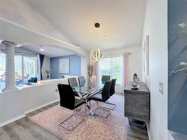 dining space featuring a textured ceiling, a notable chandelier, lofted ceiling, and hardwood / wood-style floors