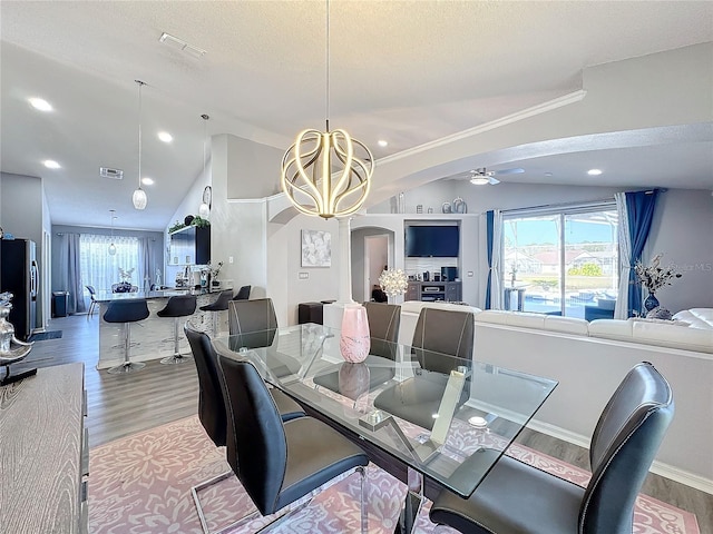 dining area with a textured ceiling, lofted ceiling, ceiling fan with notable chandelier, and wood-type flooring