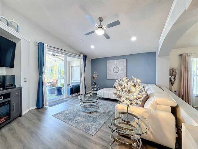 living room featuring vaulted ceiling, ceiling fan, a textured ceiling, and hardwood / wood-style floors