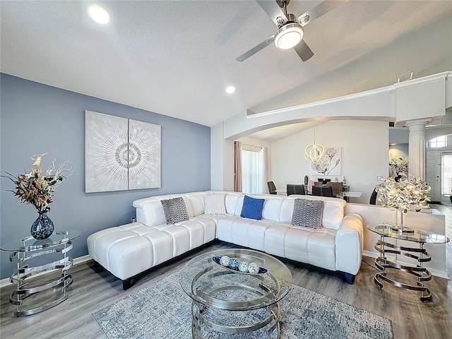 living room featuring lofted ceiling, ceiling fan, wood-type flooring, a textured ceiling, and ornate columns