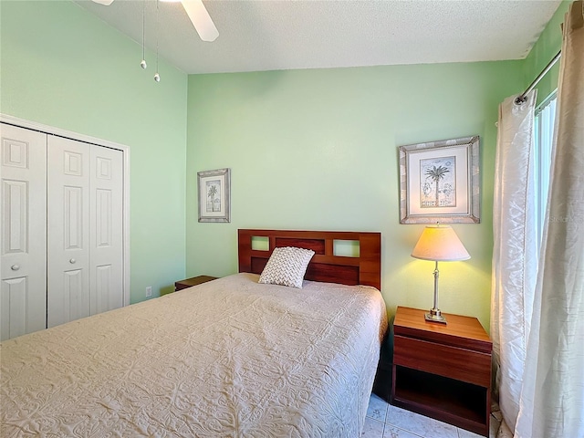 bedroom featuring ceiling fan, lofted ceiling, light tile patterned flooring, a textured ceiling, and a closet