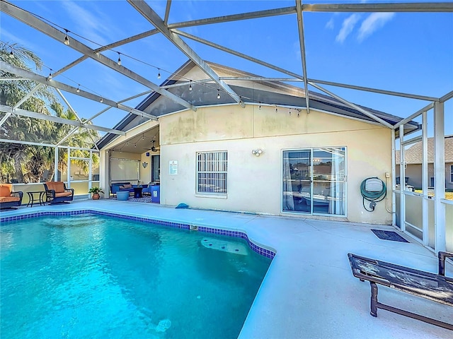 view of swimming pool with glass enclosure, a patio area, and ceiling fan