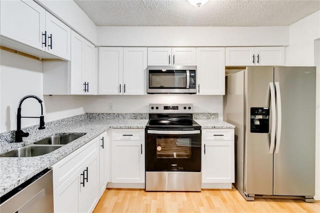 kitchen with white cabinets, sink, stainless steel appliances, and a textured ceiling