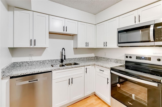 kitchen with light stone counters, sink, white cabinetry, and stainless steel appliances