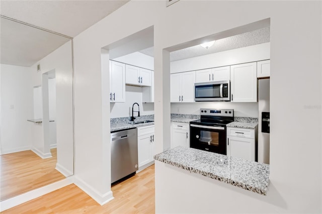 kitchen featuring white cabinets, light wood-type flooring, appliances with stainless steel finishes, and sink