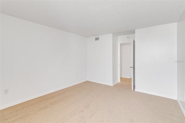 unfurnished room featuring a textured ceiling and light carpet