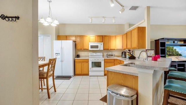 kitchen with white appliances, a kitchen breakfast bar, sink, kitchen peninsula, and a chandelier