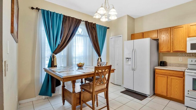 kitchen with decorative light fixtures, white appliances, a notable chandelier, and light tile patterned flooring