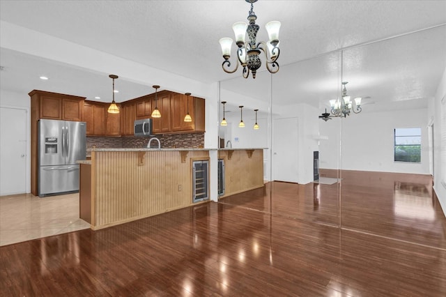 kitchen featuring a kitchen breakfast bar, stainless steel appliances, tasteful backsplash, a notable chandelier, and kitchen peninsula