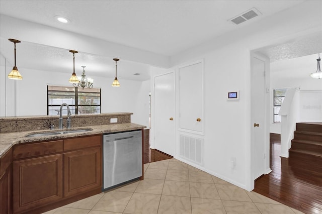 kitchen with pendant lighting, stainless steel dishwasher, light stone countertops, and sink