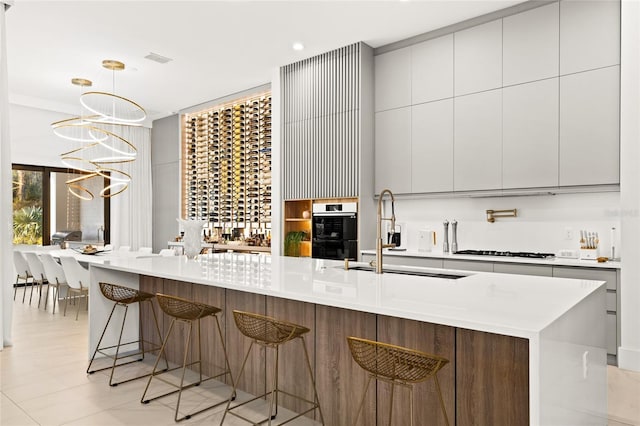 kitchen featuring a kitchen bar, a large island with sink, hanging light fixtures, and sink