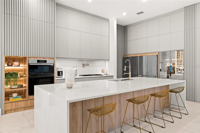 kitchen with a large island, built in fridge, double oven, a breakfast bar, and sink