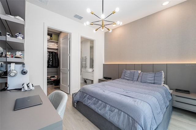 bedroom with connected bathroom, light hardwood / wood-style flooring, and a chandelier