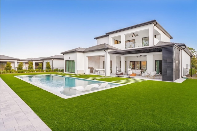 back of house featuring ceiling fan, outdoor lounge area, a patio, a balcony, and a fenced in pool