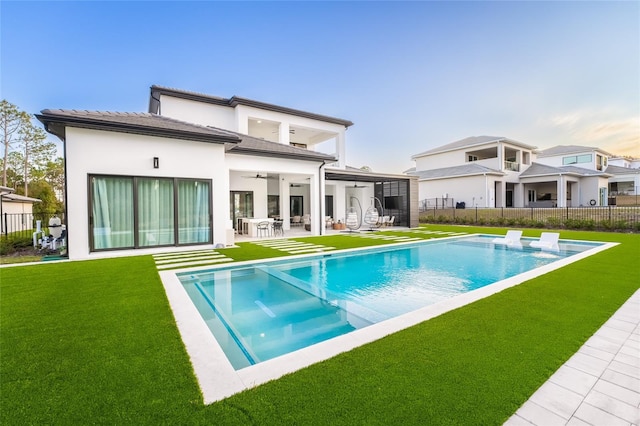 rear view of property with ceiling fan, a yard, a patio area, and a fenced in pool