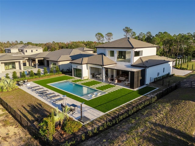 back of house featuring an outdoor hangout area, a fenced in pool, a patio area, and a lawn