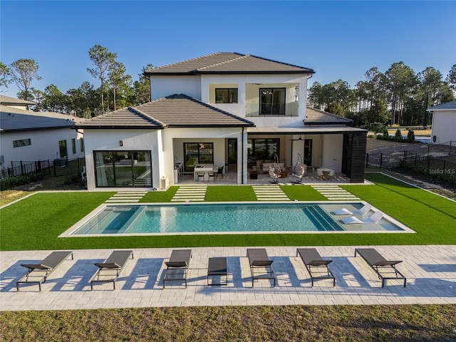 back of property featuring a lawn, a patio, and a fenced in pool