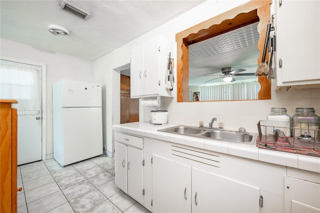 kitchen featuring sink, white cabinetry, white refrigerator, tile counters, and decorative backsplash