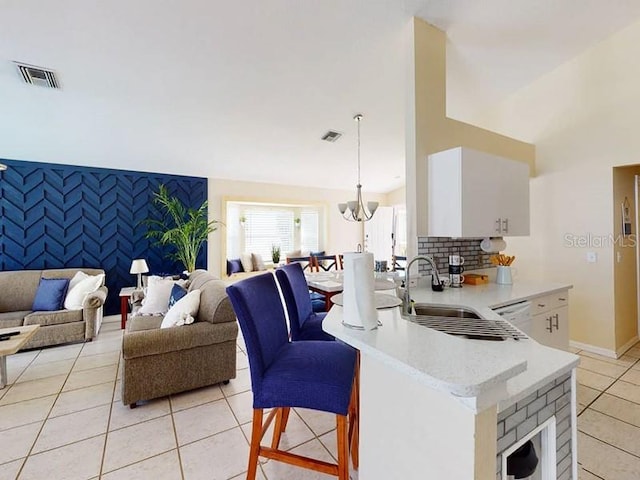 kitchen featuring light tile patterned floors, sink, white cabinetry, and pendant lighting