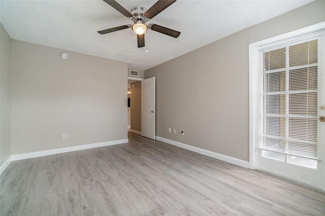 spare room featuring ceiling fan, light hardwood / wood-style flooring, and a textured ceiling