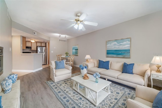 living room with ceiling fan and light wood-type flooring