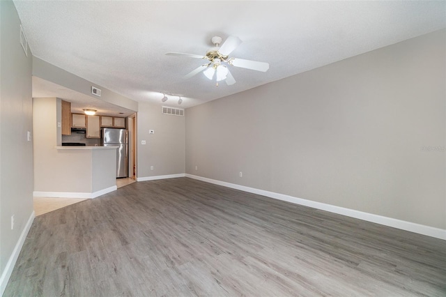 unfurnished living room with a textured ceiling, light hardwood / wood-style flooring, and ceiling fan