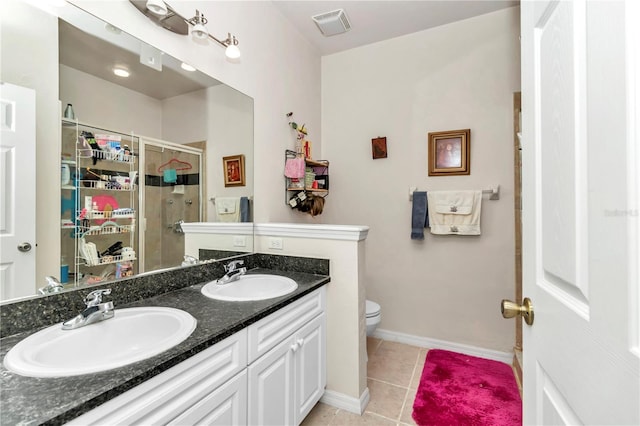 bathroom featuring toilet, vanity, a shower with door, and tile patterned floors