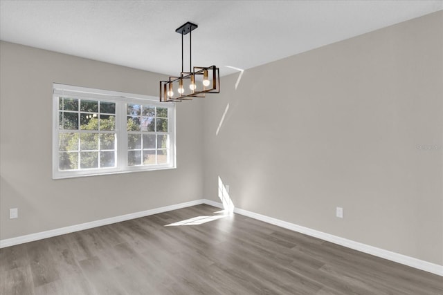 unfurnished dining area with wood-type flooring and a chandelier