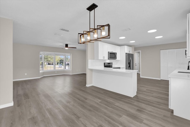 kitchen featuring pendant lighting, white cabinets, stainless steel appliances, kitchen peninsula, and ceiling fan