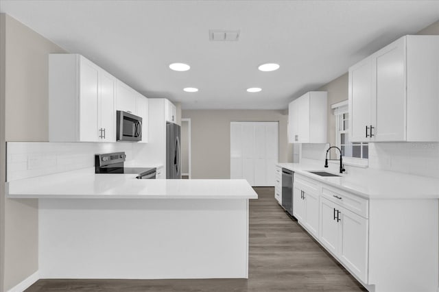 kitchen featuring kitchen peninsula, stainless steel appliances, white cabinetry, and sink