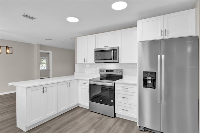 kitchen featuring kitchen peninsula, stainless steel appliances, and white cabinetry