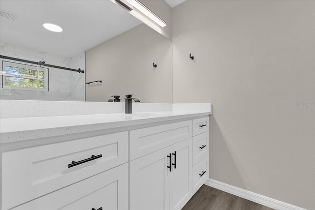 bathroom with wood-type flooring, walk in shower, and vanity