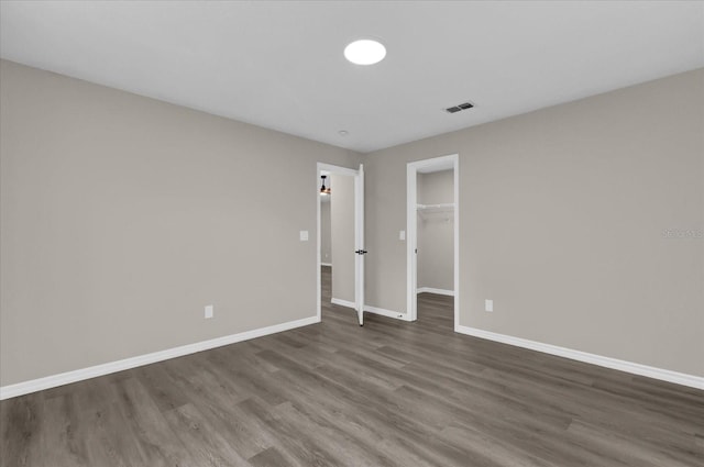 unfurnished bedroom with dark wood-type flooring, a closet, and a spacious closet