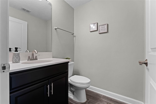 bathroom featuring vanity, hardwood / wood-style floors, a textured ceiling, and toilet