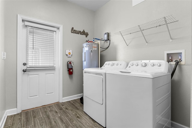 laundry room with dark wood-type flooring, washing machine and dryer, and electric water heater