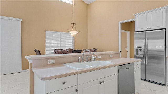 kitchen with white cabinets, appliances with stainless steel finishes, decorative light fixtures, sink, and light tile patterned floors