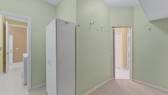 hall with light tile patterned flooring and washer / dryer