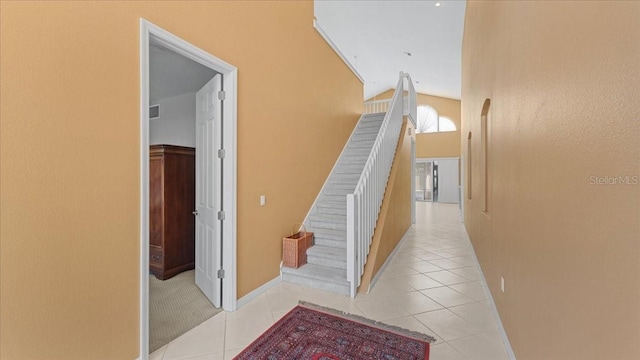 hall featuring lofted ceiling and light tile patterned flooring