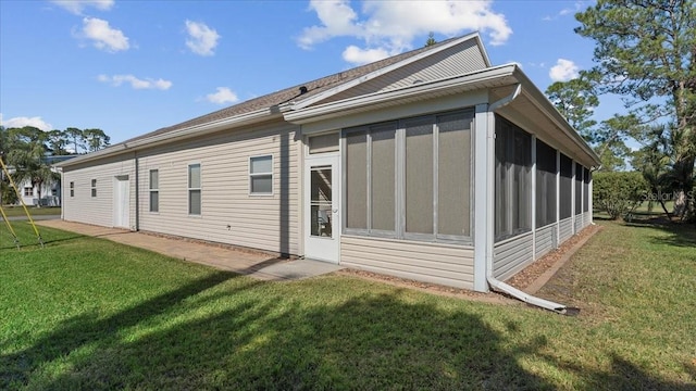 back of house featuring a lawn and a sunroom